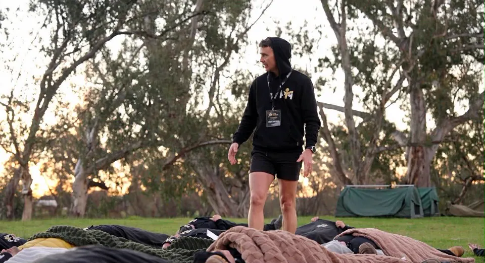 Early morning at camp — a facilitator walking among the men still resting in their swags under the gums