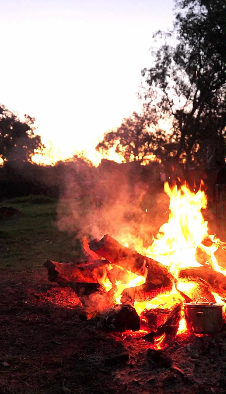 The campfire burning down at dusk